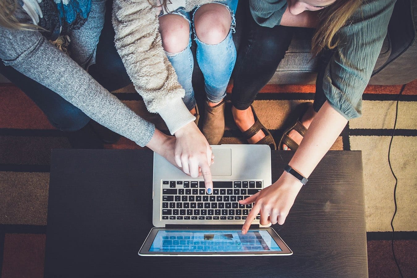 Hands pointing at a laptop keyboard and a tablet