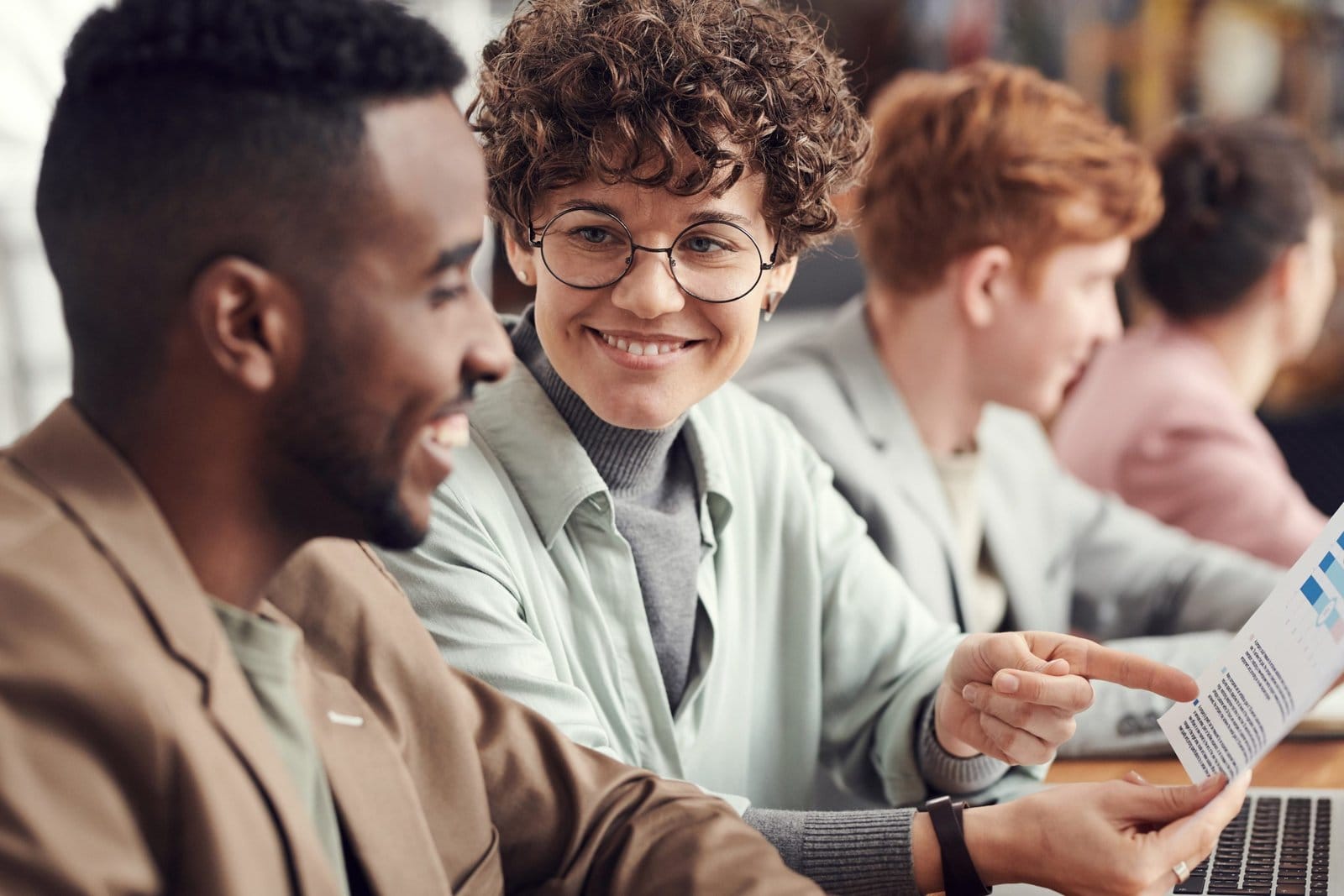 Colleagues smiling and discussing a printed document at a table