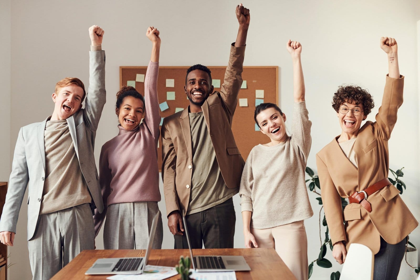 Five colleagues raising their fists in celebration behind a desk