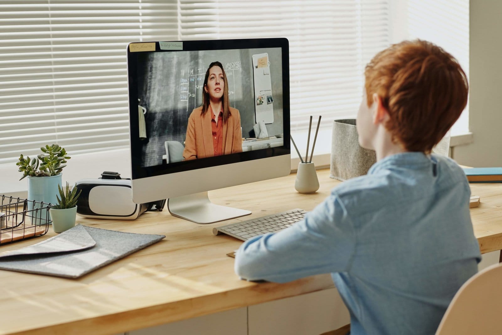 A child watching a video call on a desktop monitor