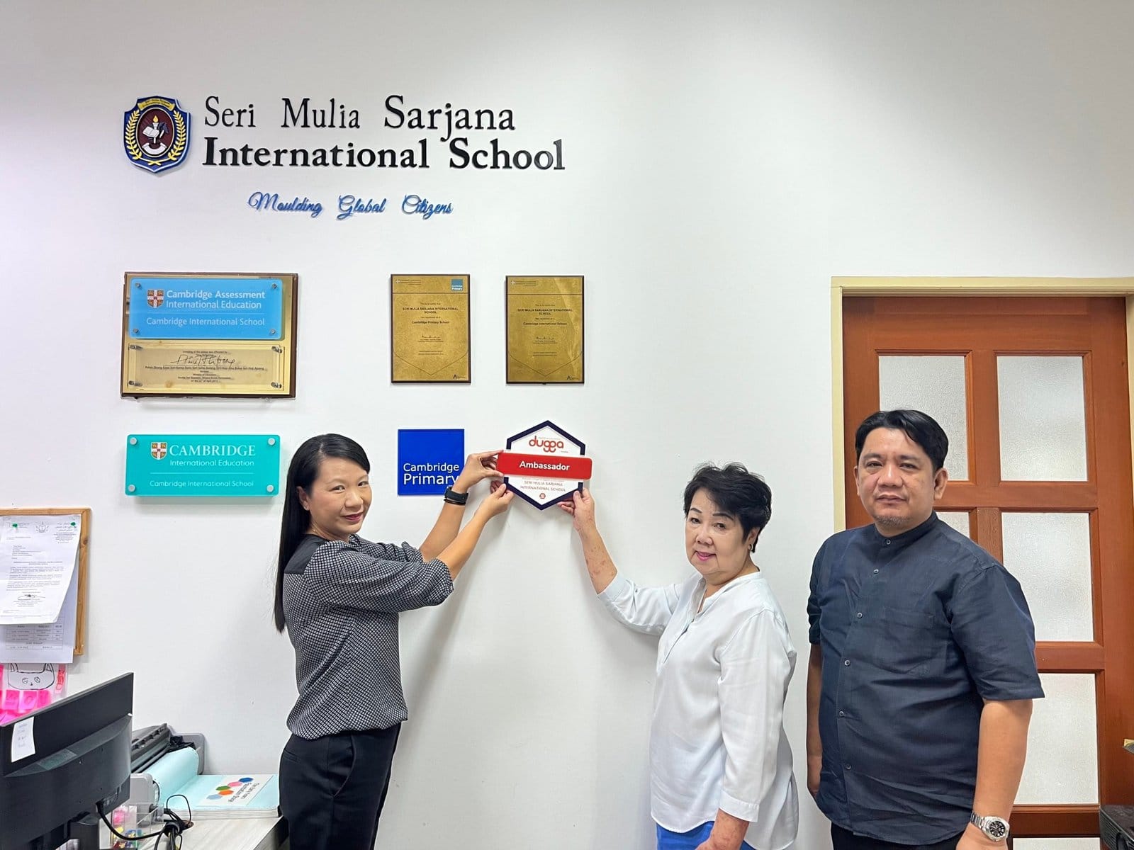 Staff at Seri Mulia Sarjana International School hanging the Dugga Ambassador badge on the wall