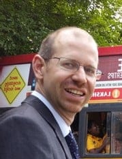 Paul Baker, a smiling man in glasses and a dark suit.
